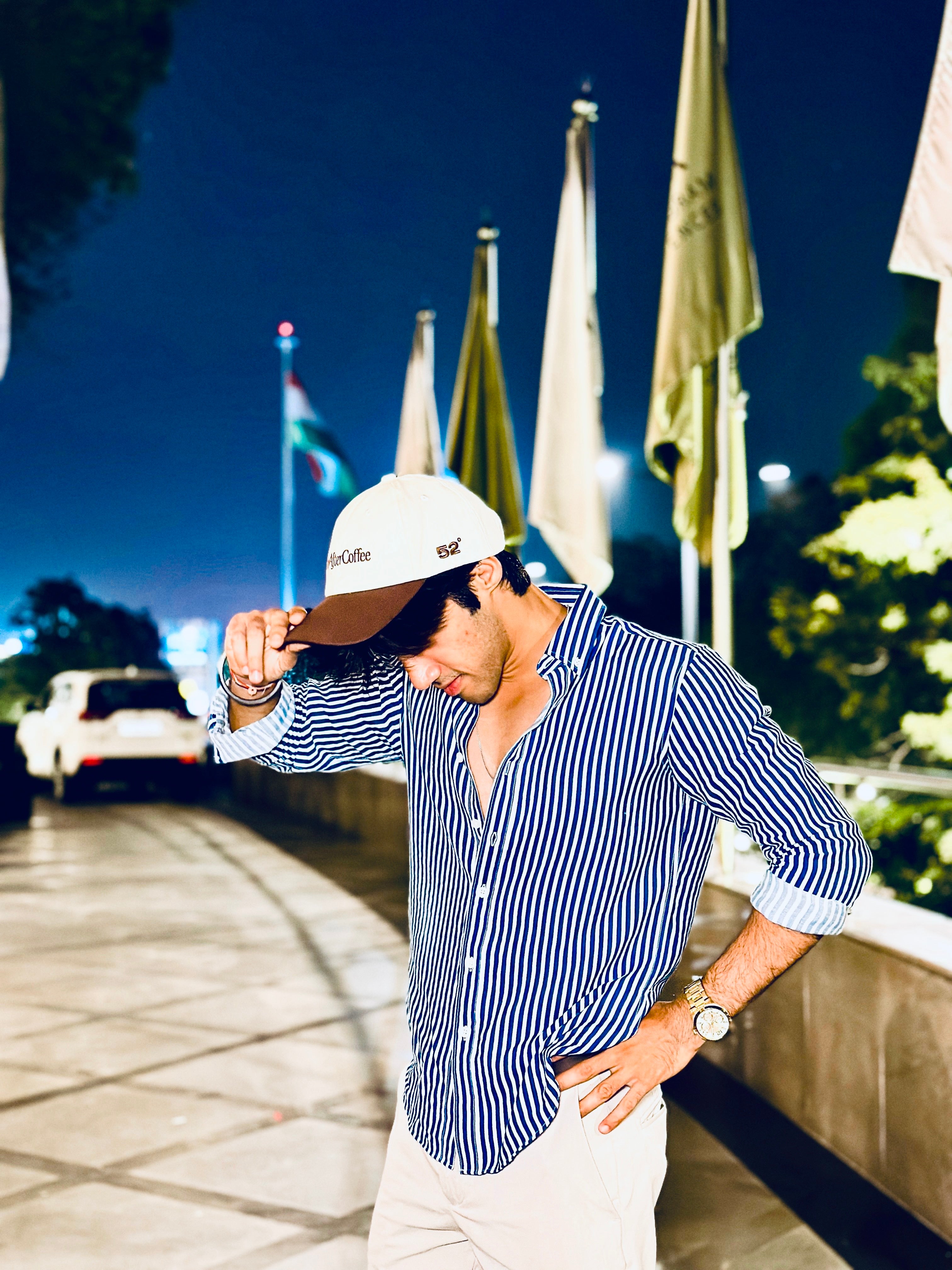 Man adjusting a cap with flags and a car in the background