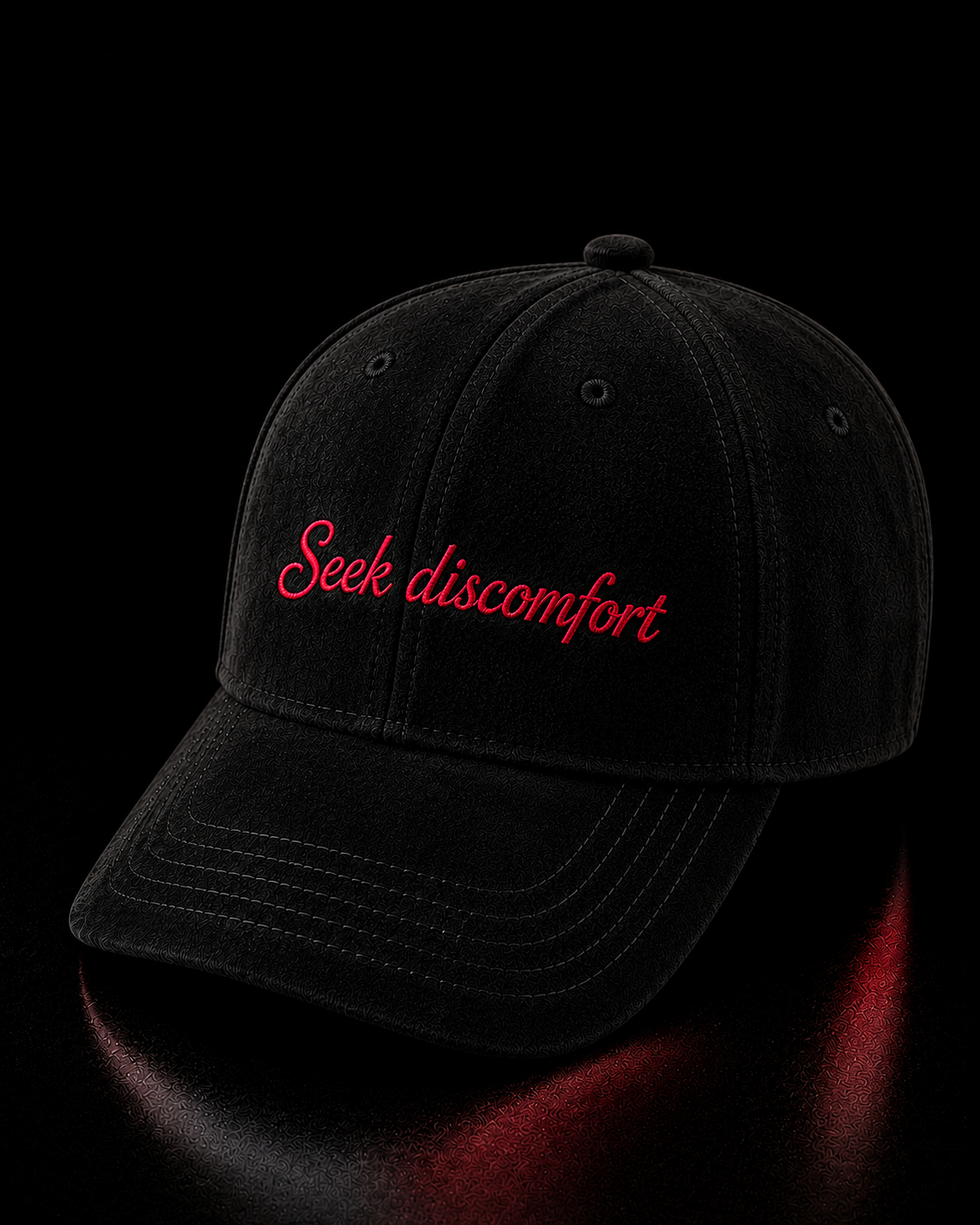 Black cap with 'Seek discomfort' text in red on a reflective black surface.