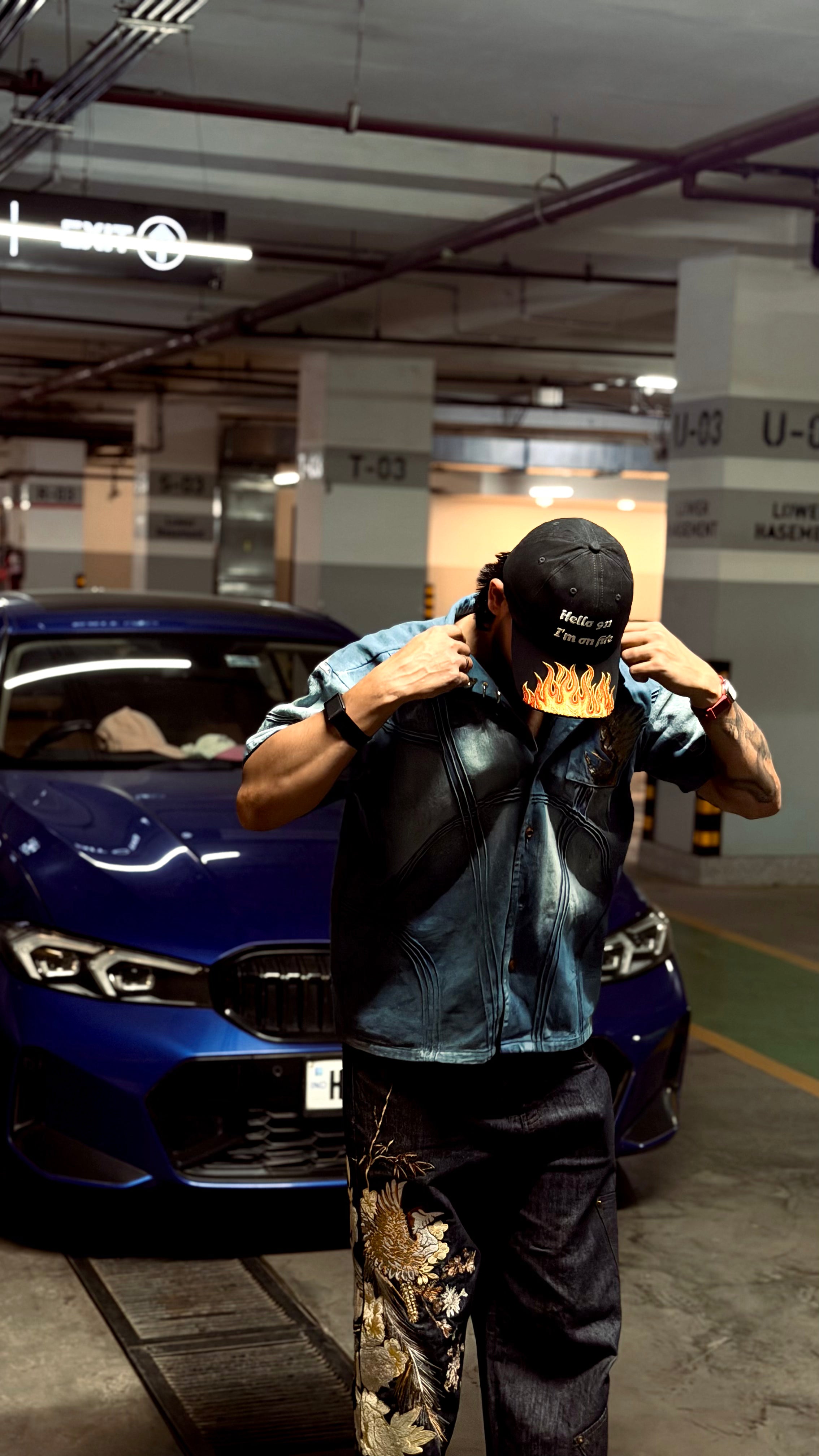Person wearing a black leather jacket with flame design in a parking garage.