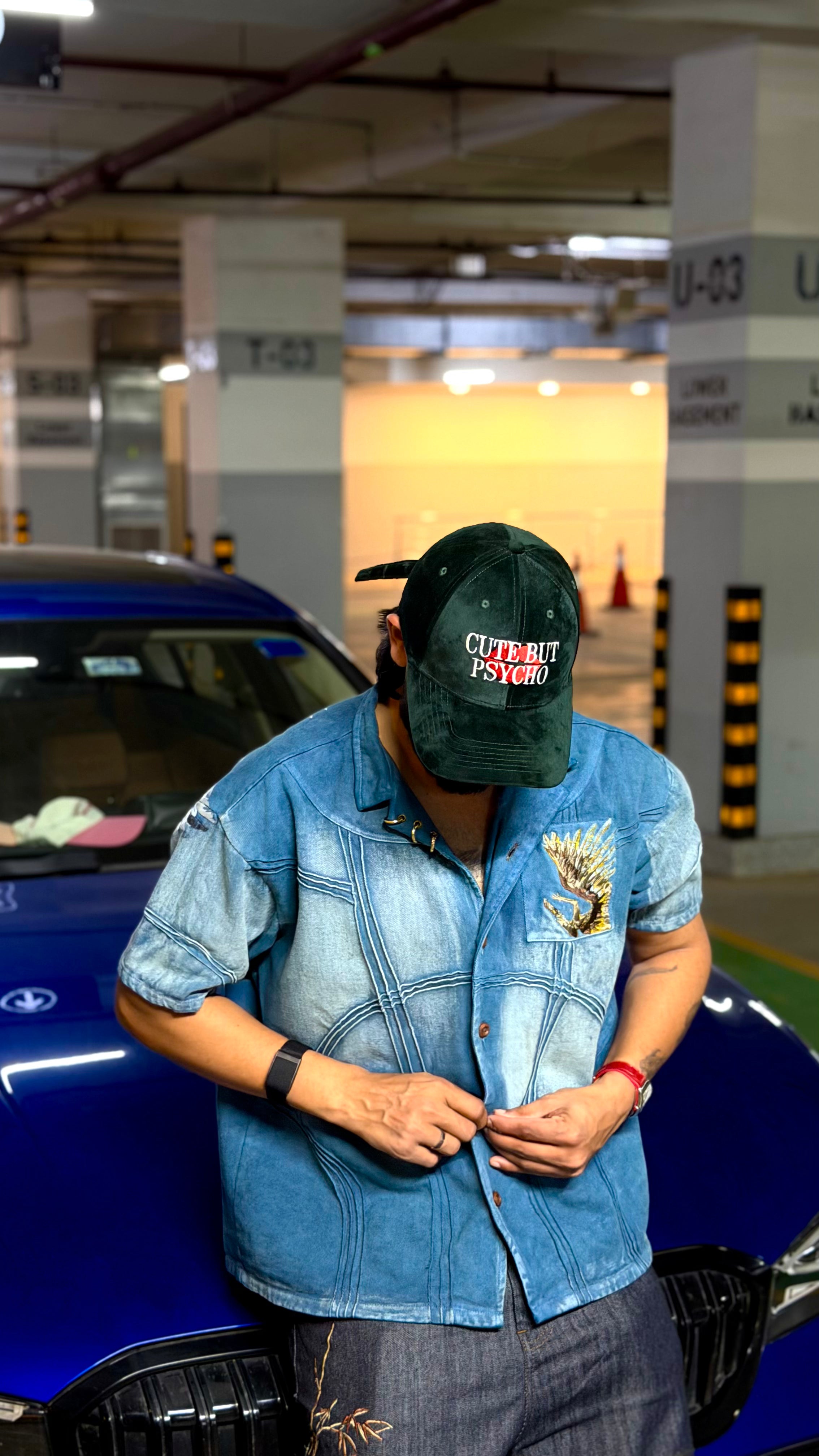 Person wearing a denim jacket and cap in a parking garage