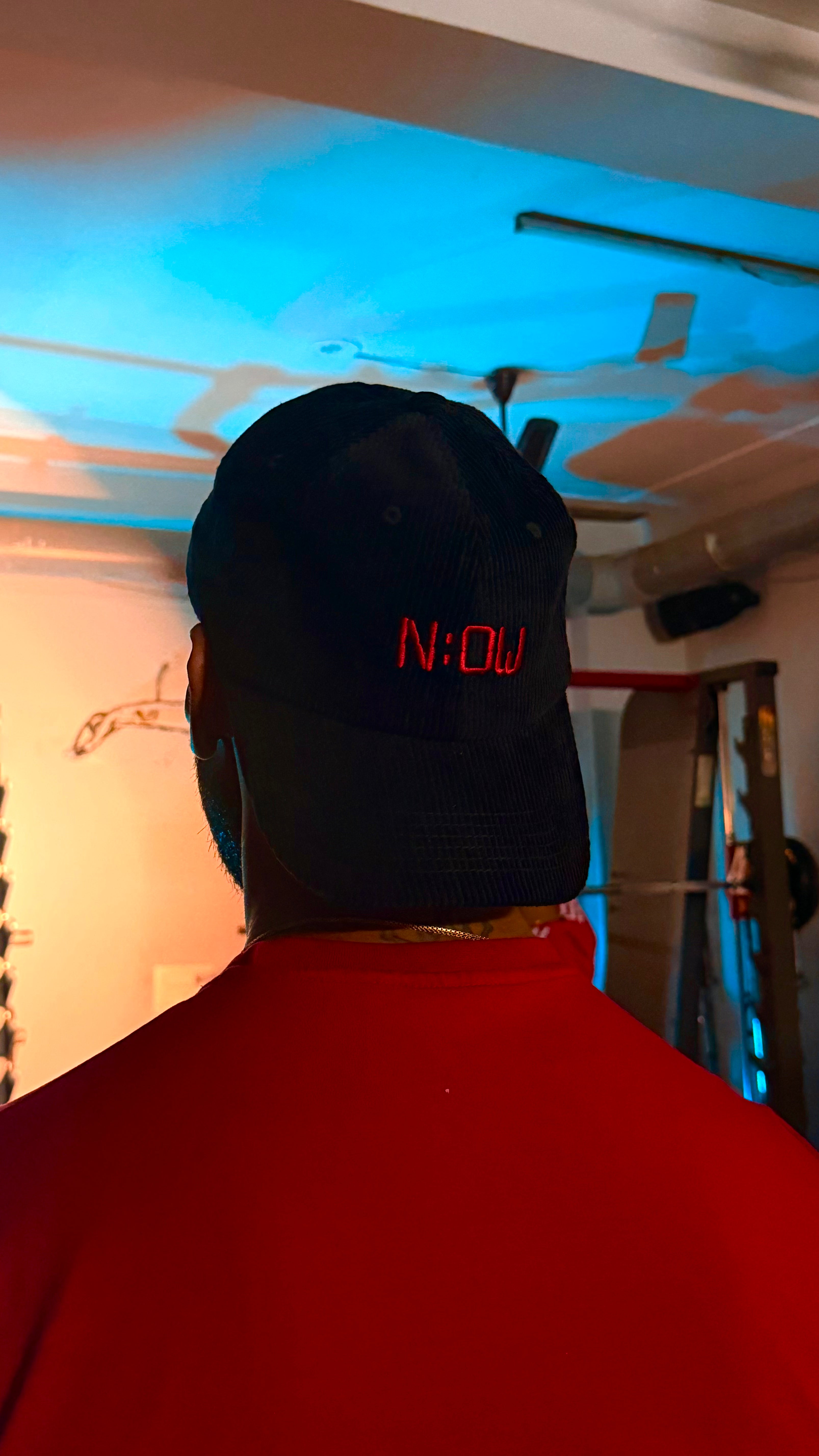 Person wearing a black cap with red text in an indoor setting