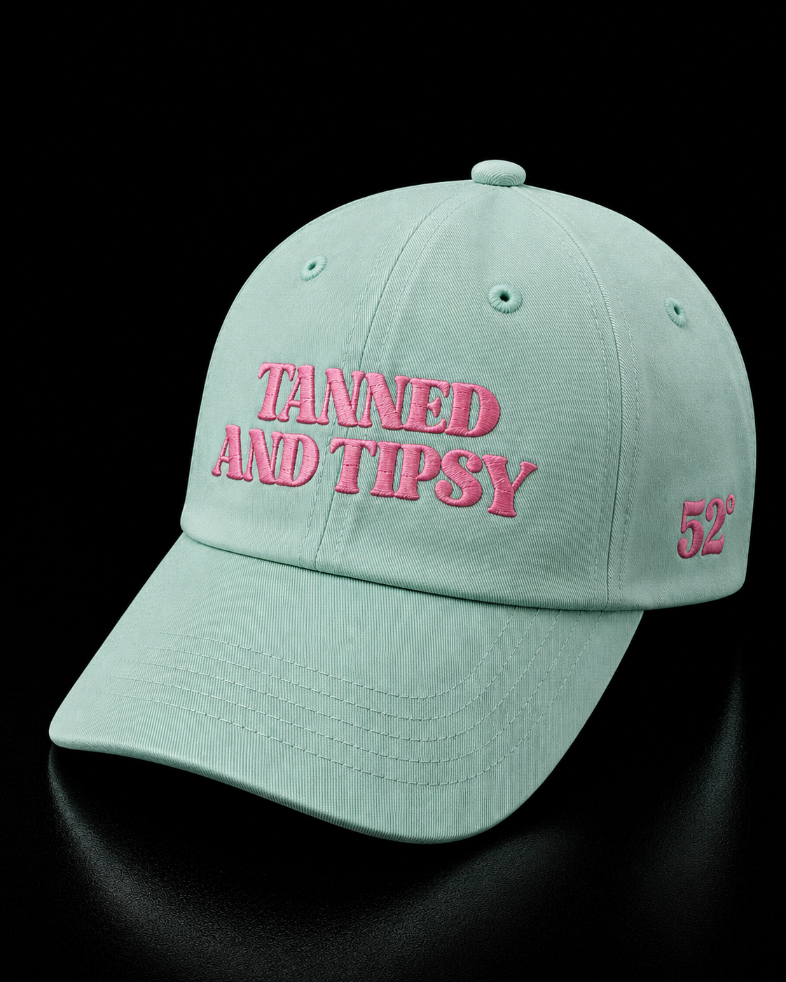 Light blue cap with pink text 'Tanned and Tipsy' on a black background