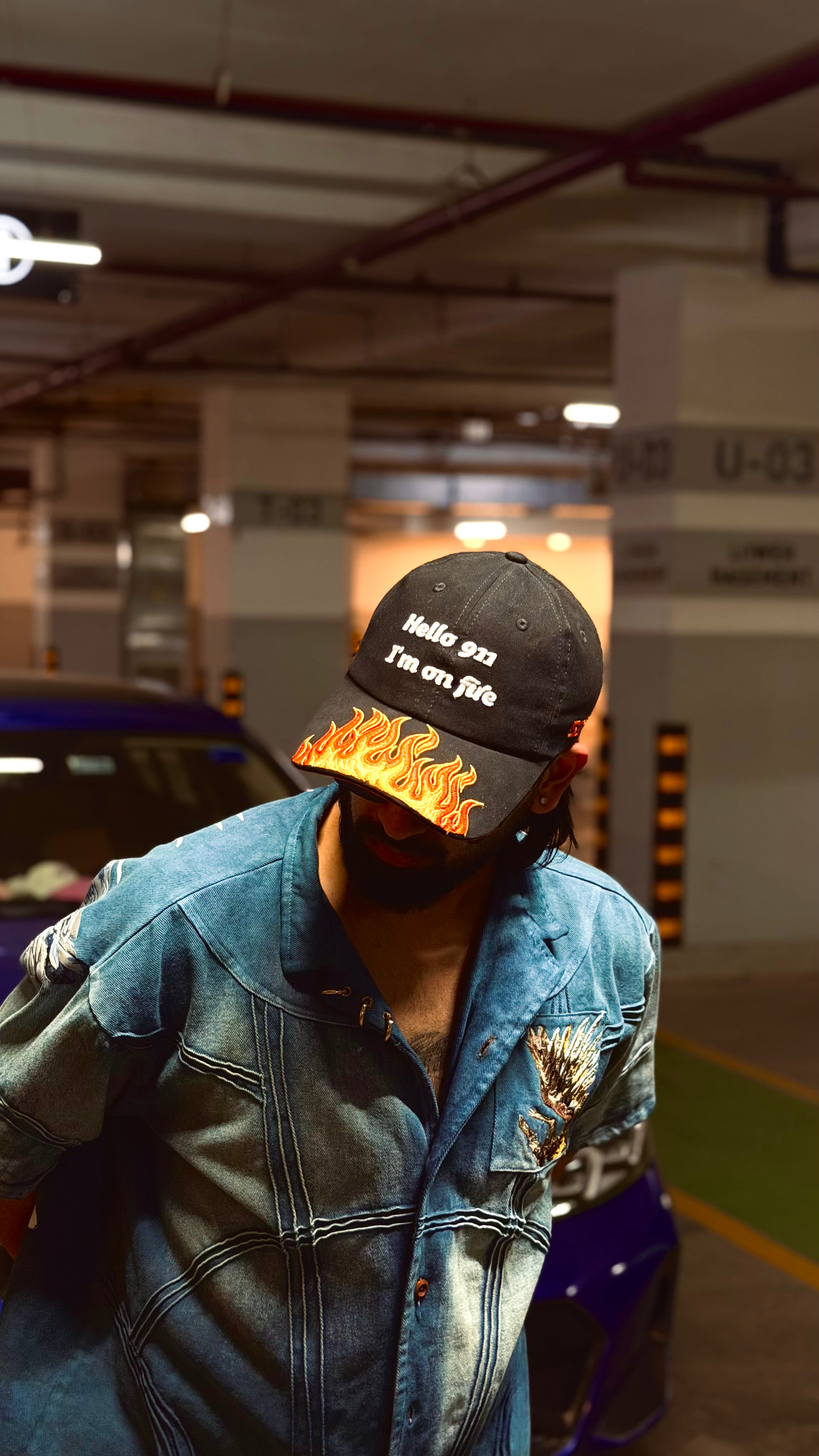 Person wearing a cap with text and flame design in an indoor setting