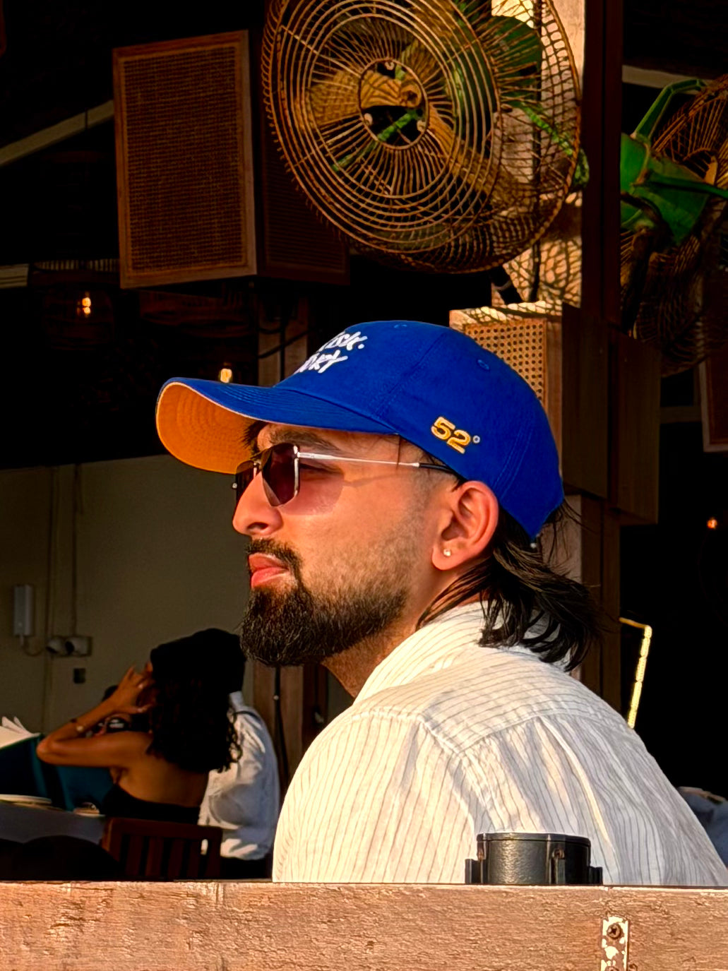 Man wearing a blue and orange cap and sunglasses in a casual setting