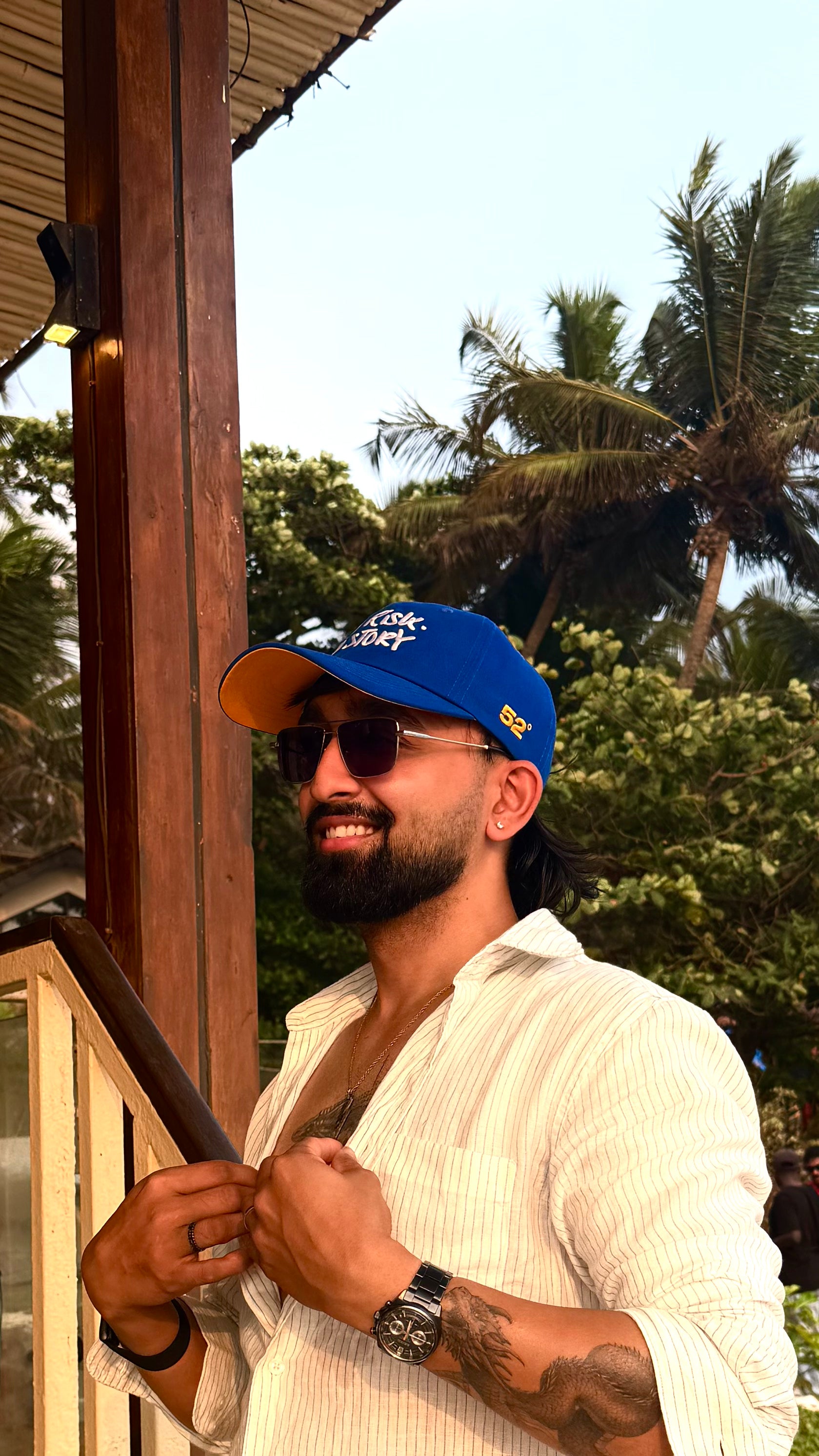 Man wearing a blue cap and sunglasses with a tropical background