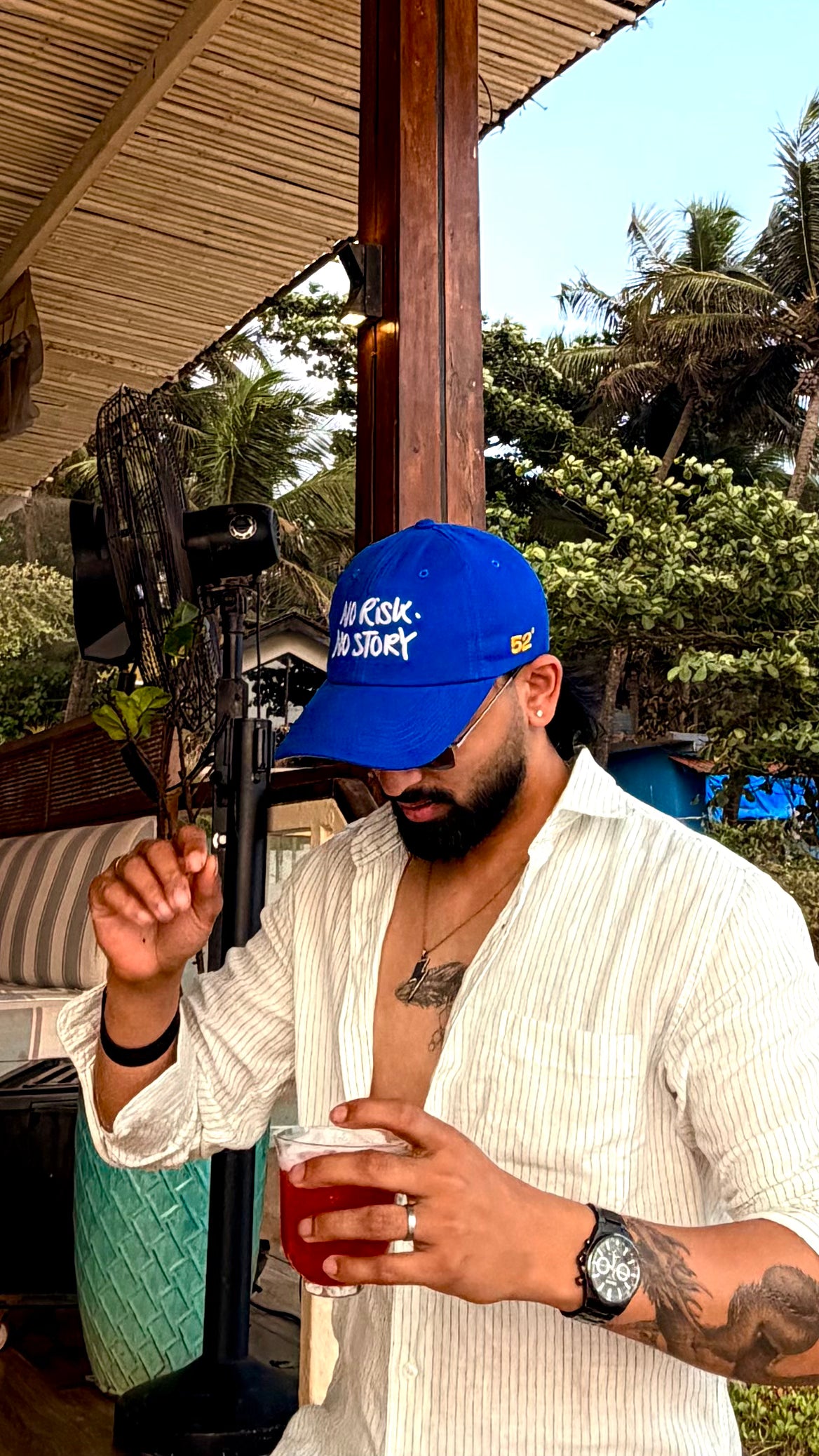 Man wearing a blue cap and white shirt holding a drink outdoors