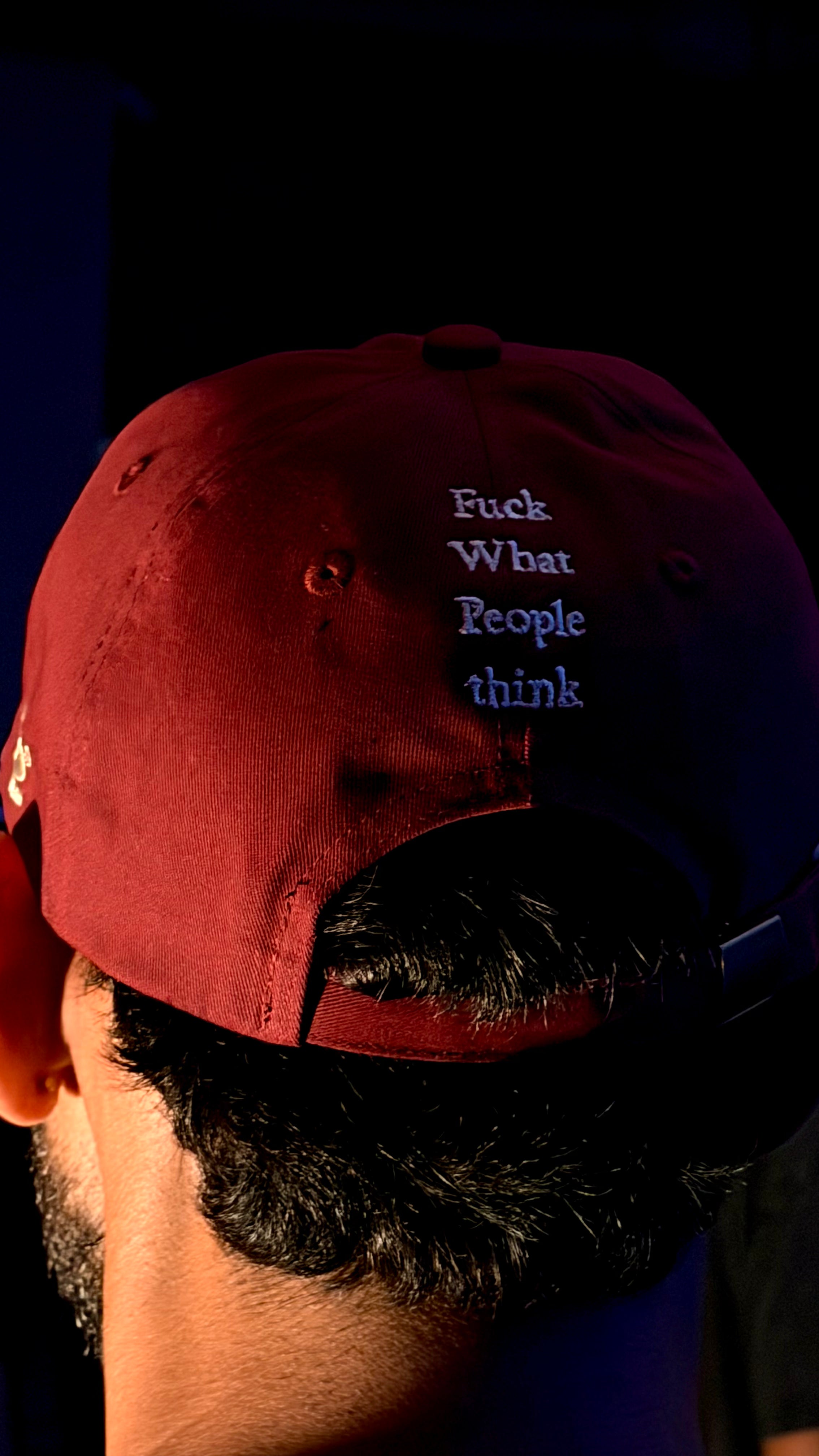 Red cap with text worn by a person against a dark background