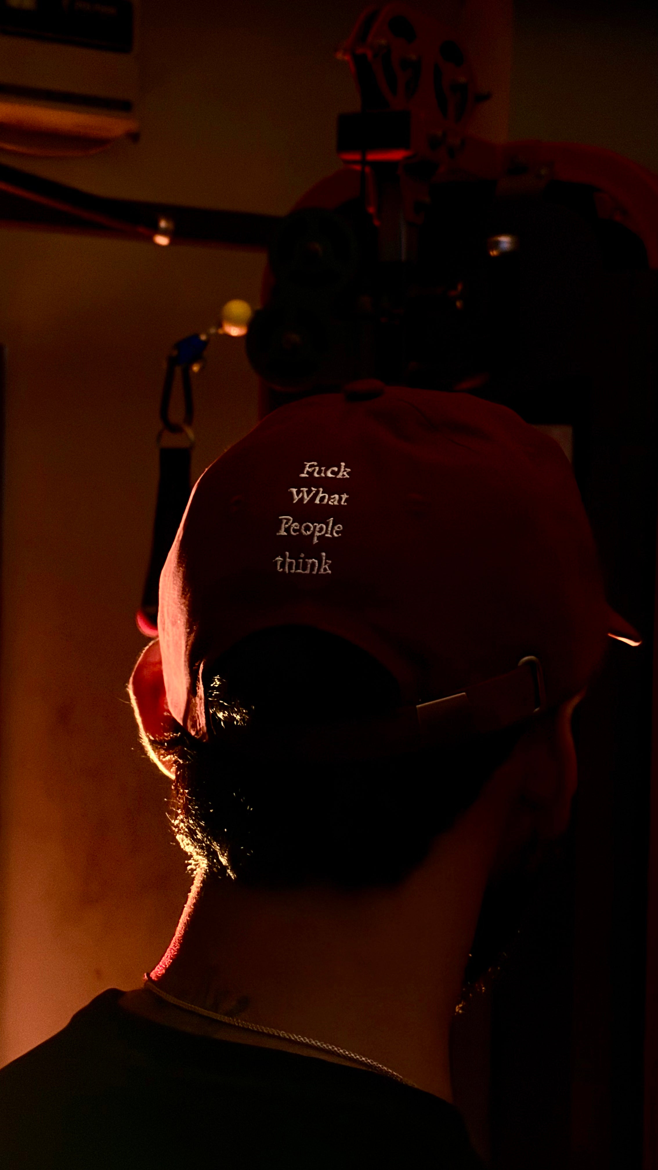 Person wearing a cap with text, backlit by a warm light source