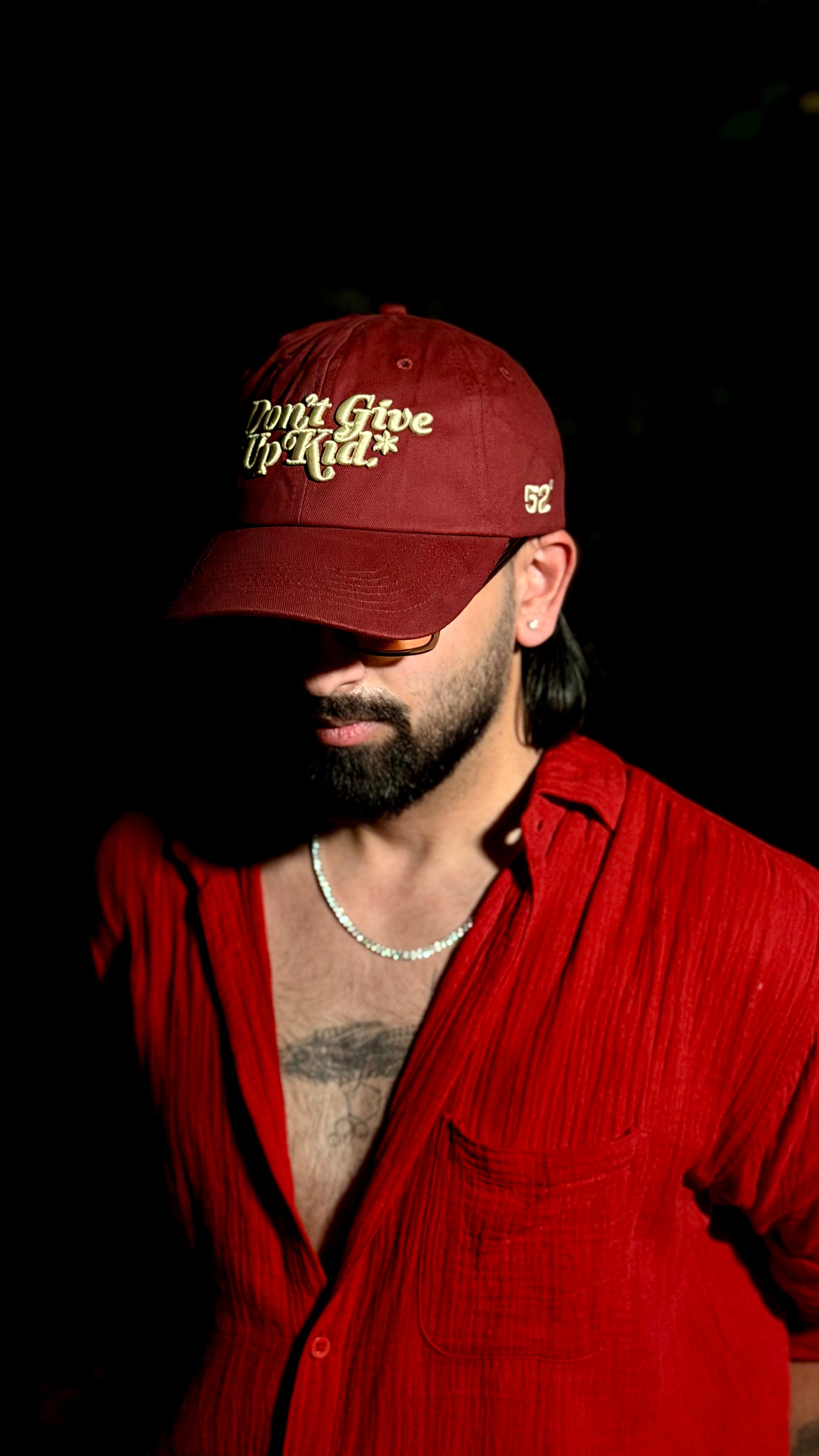 Man wearing a red cap with text and a red shirt against a dark background