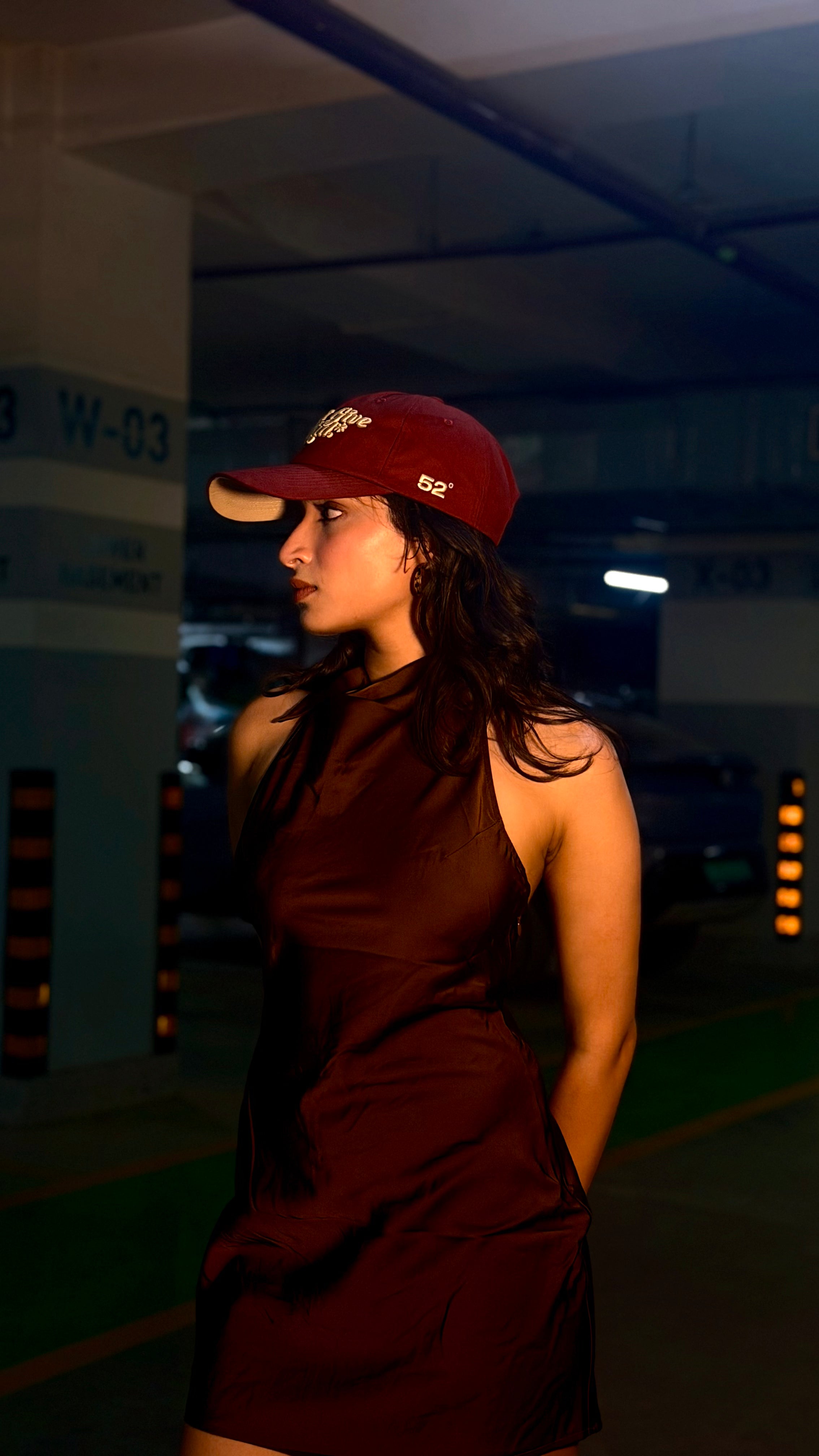 Woman wearing a red cap and dress in a dimly lit indoor setting