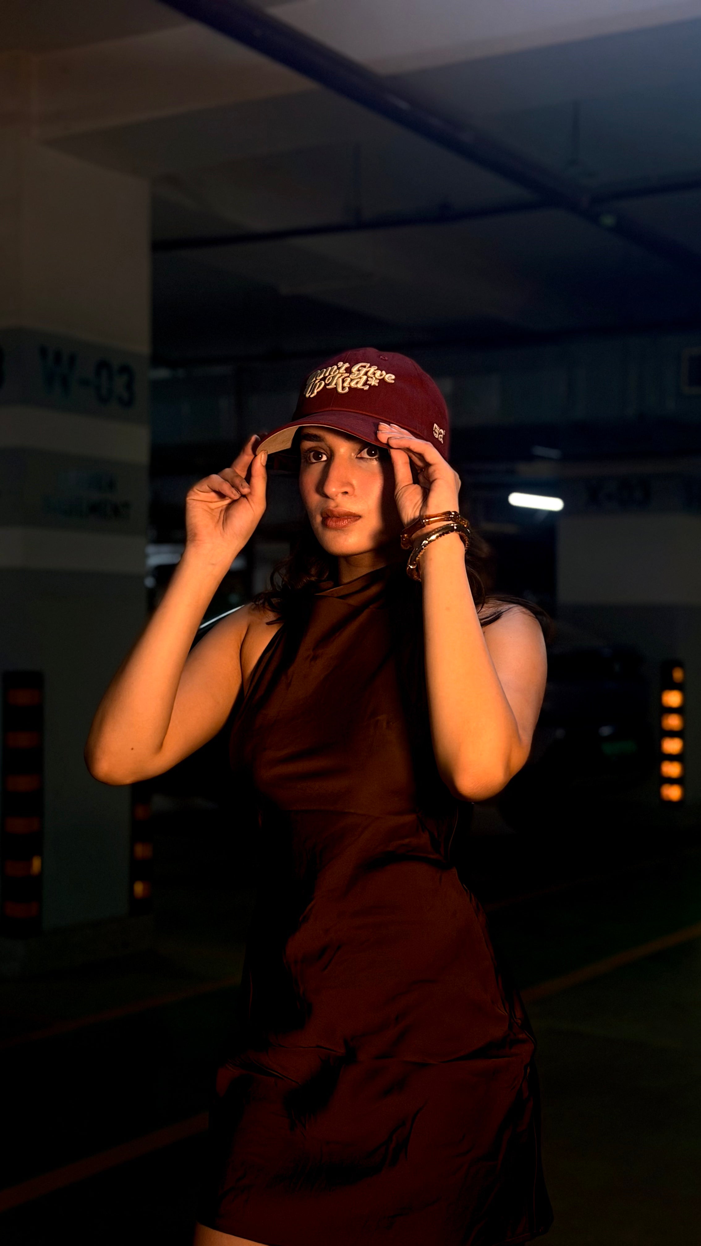 Person wearing a maroon cap in a dimly lit indoor setting